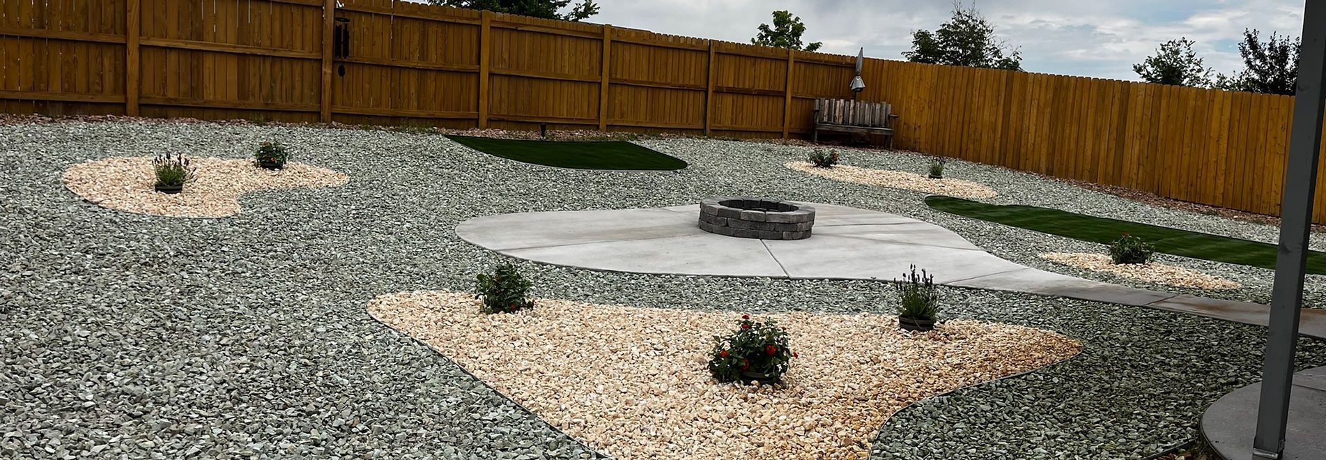 Landscaped garden bed with two spiky green plants, mulch, rocks, and shrubs behind them