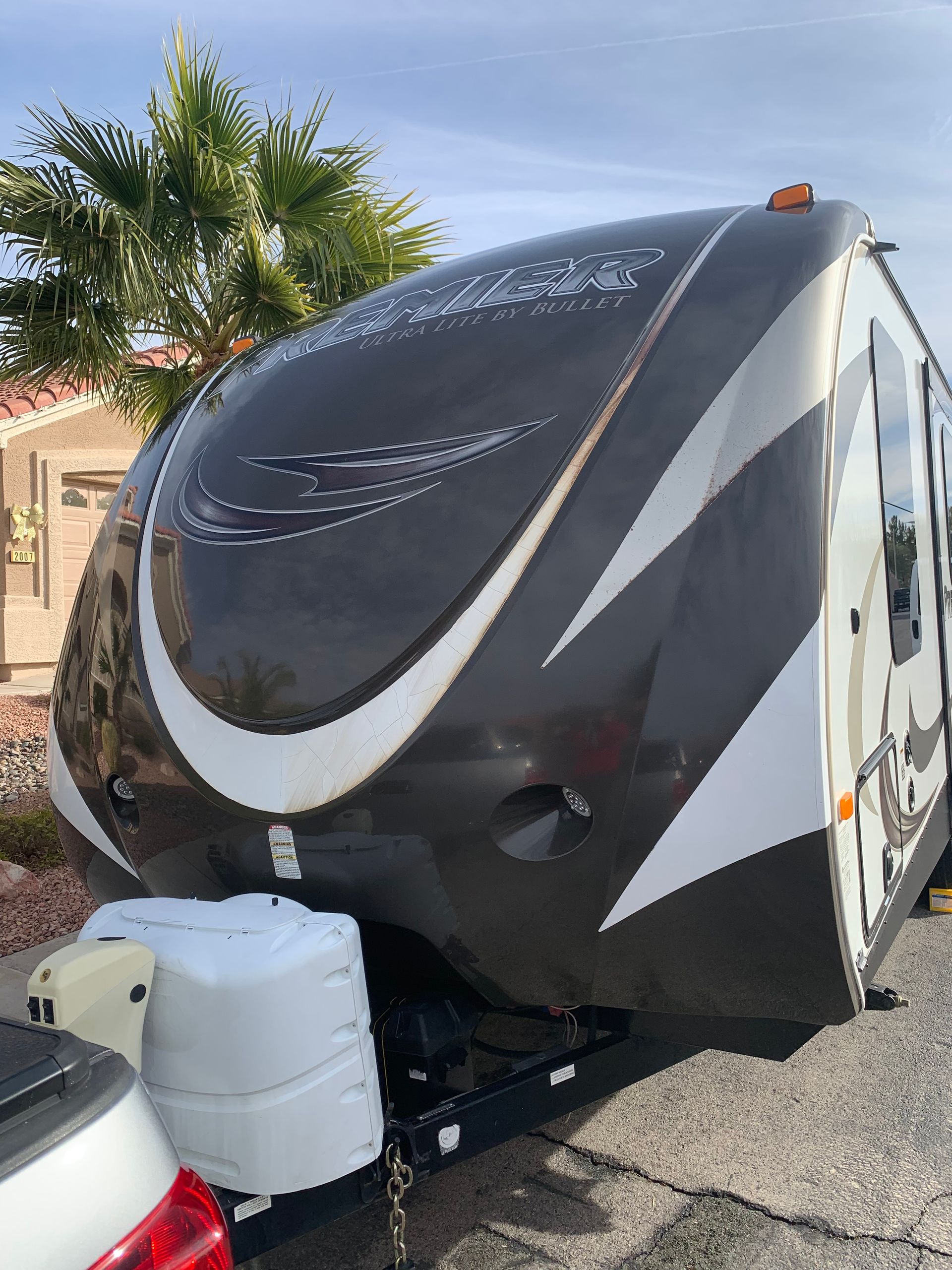 A black and white trailer is parked next to a white car.