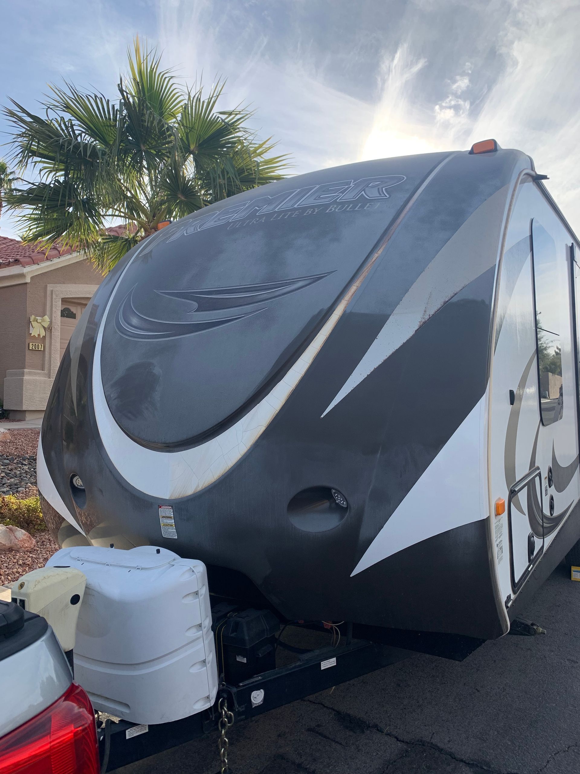 A black and white trailer is parked in front of a house.
