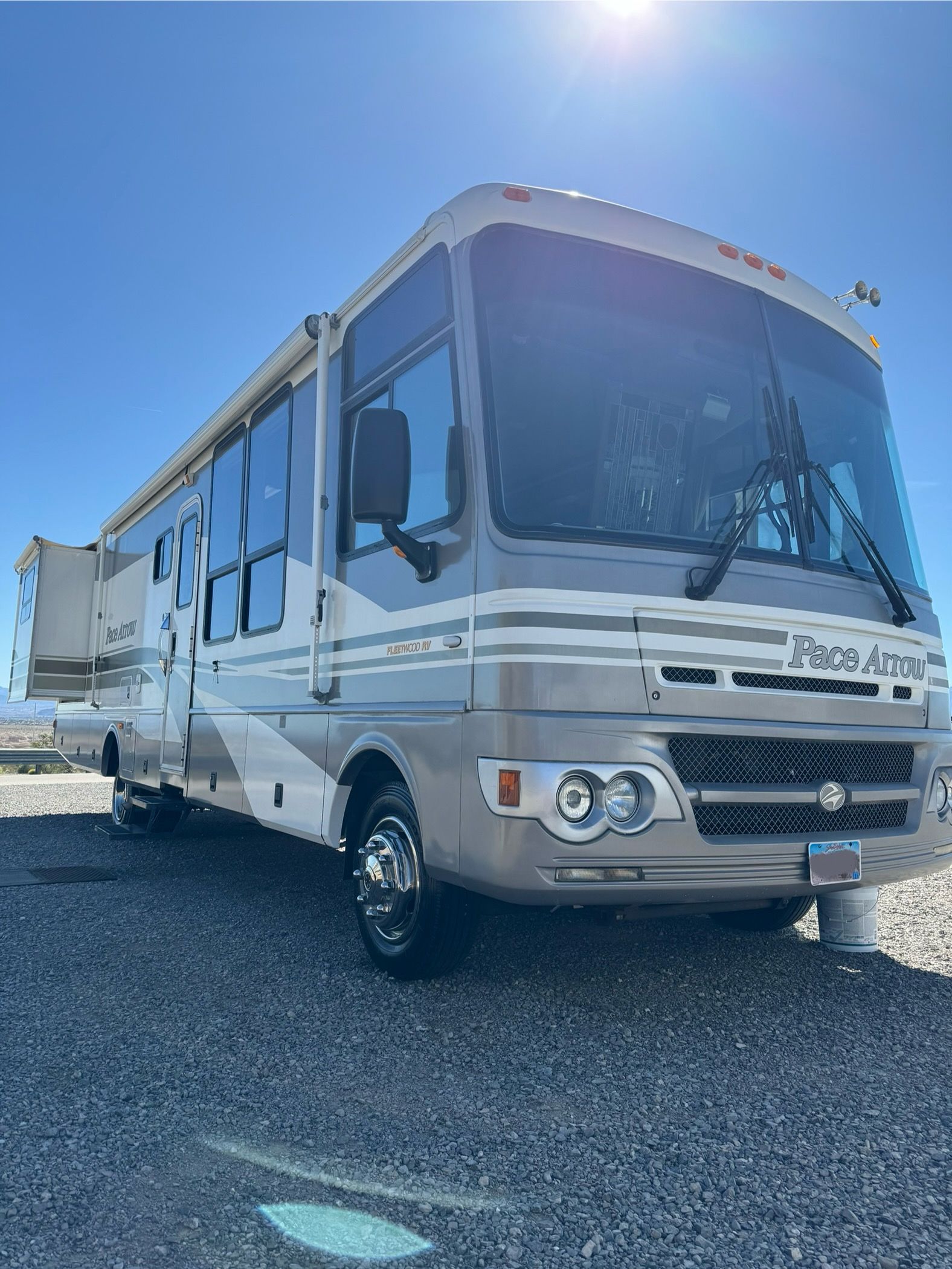 A large rv is parked in a gravel lot.