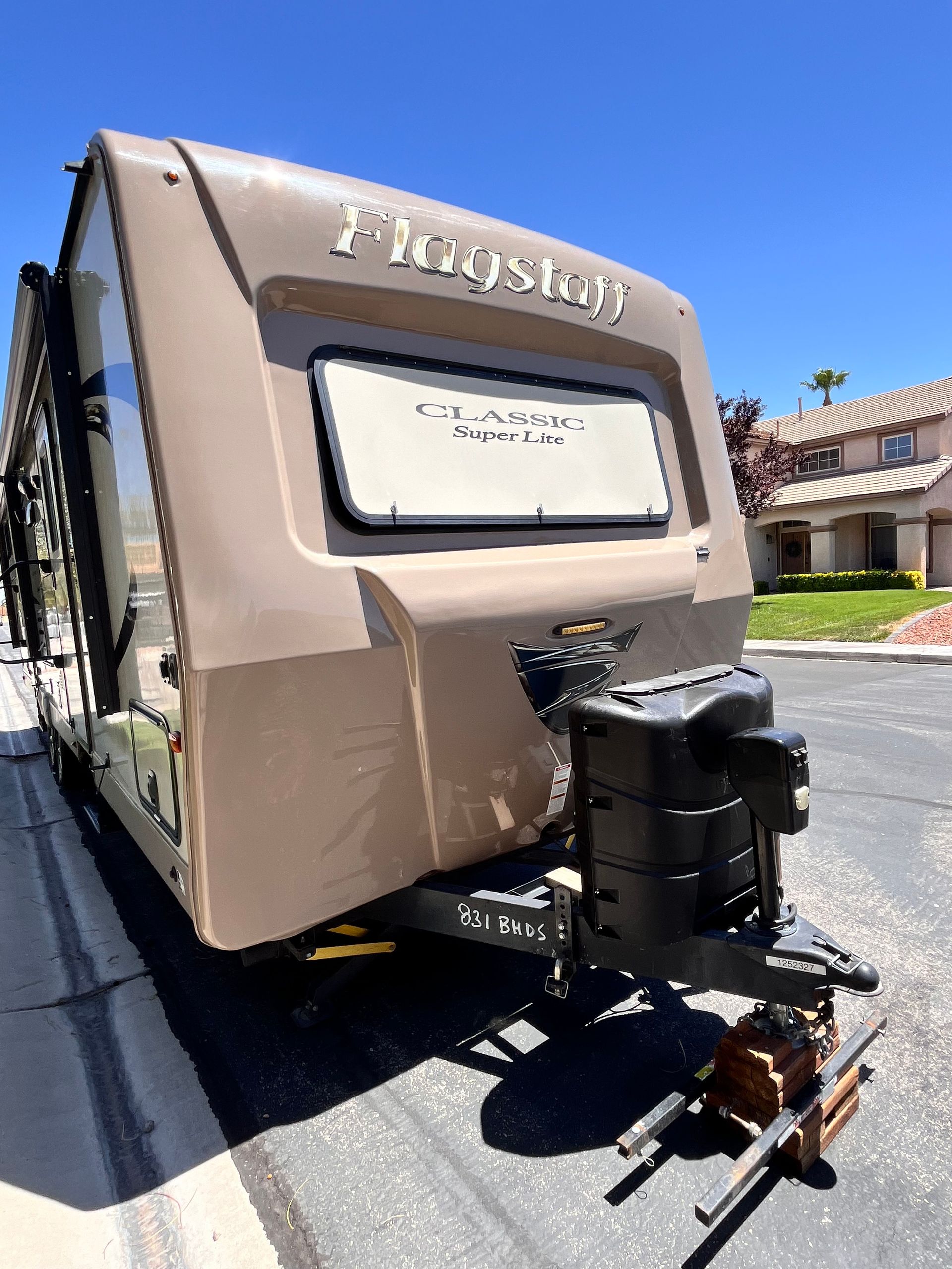 A rv is parked on the side of the road next to a house.