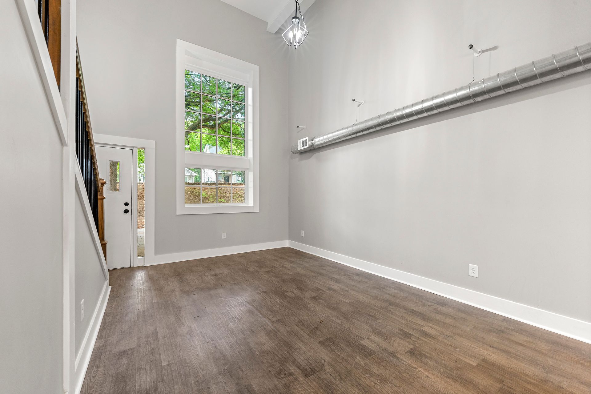 Empty walk-in closet with gray walls, wood-look floor, window, and hanging rods on both sides