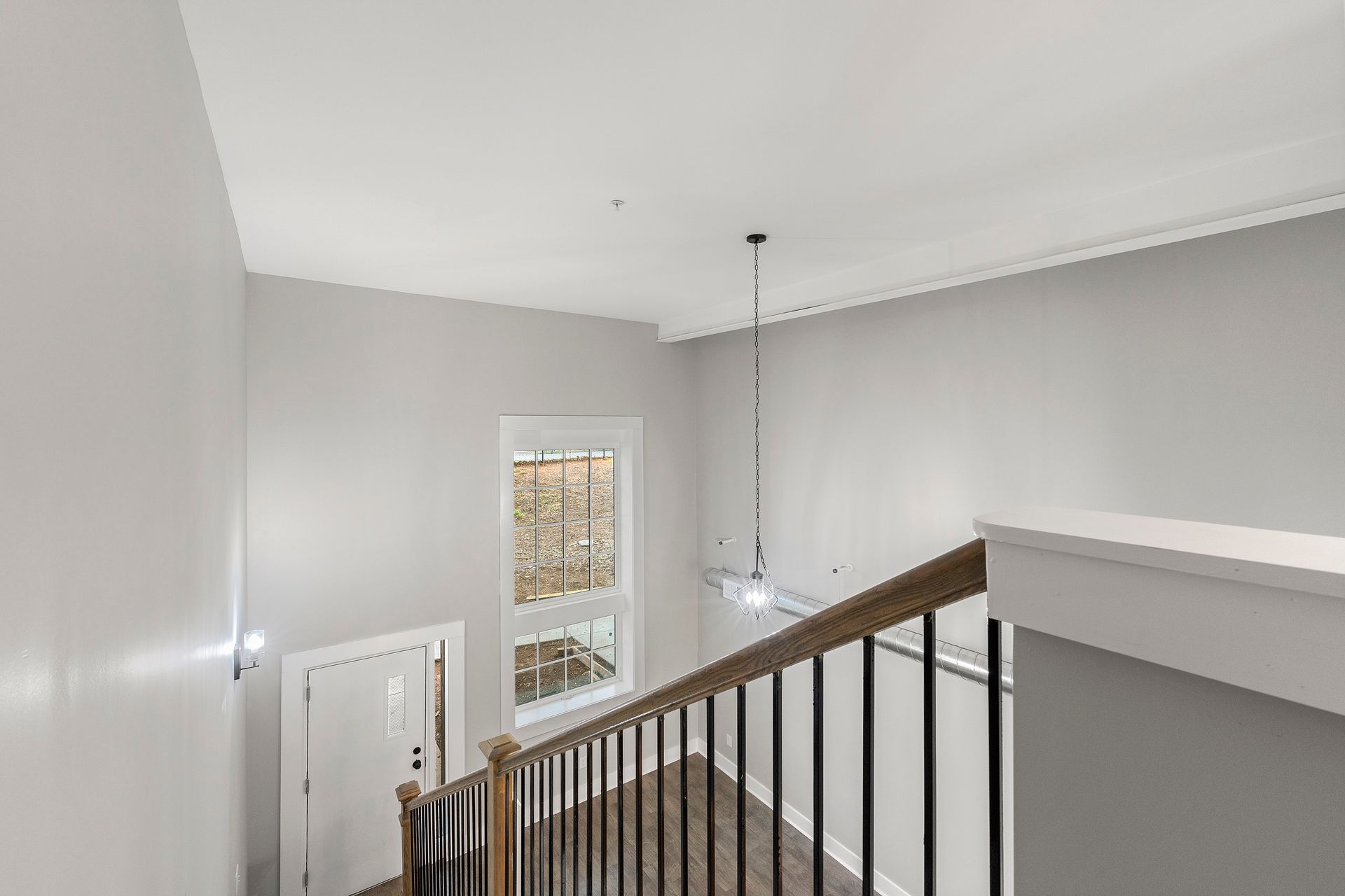 Stairway landing with gray walls, white trim, black railing, and a window letting in daylight