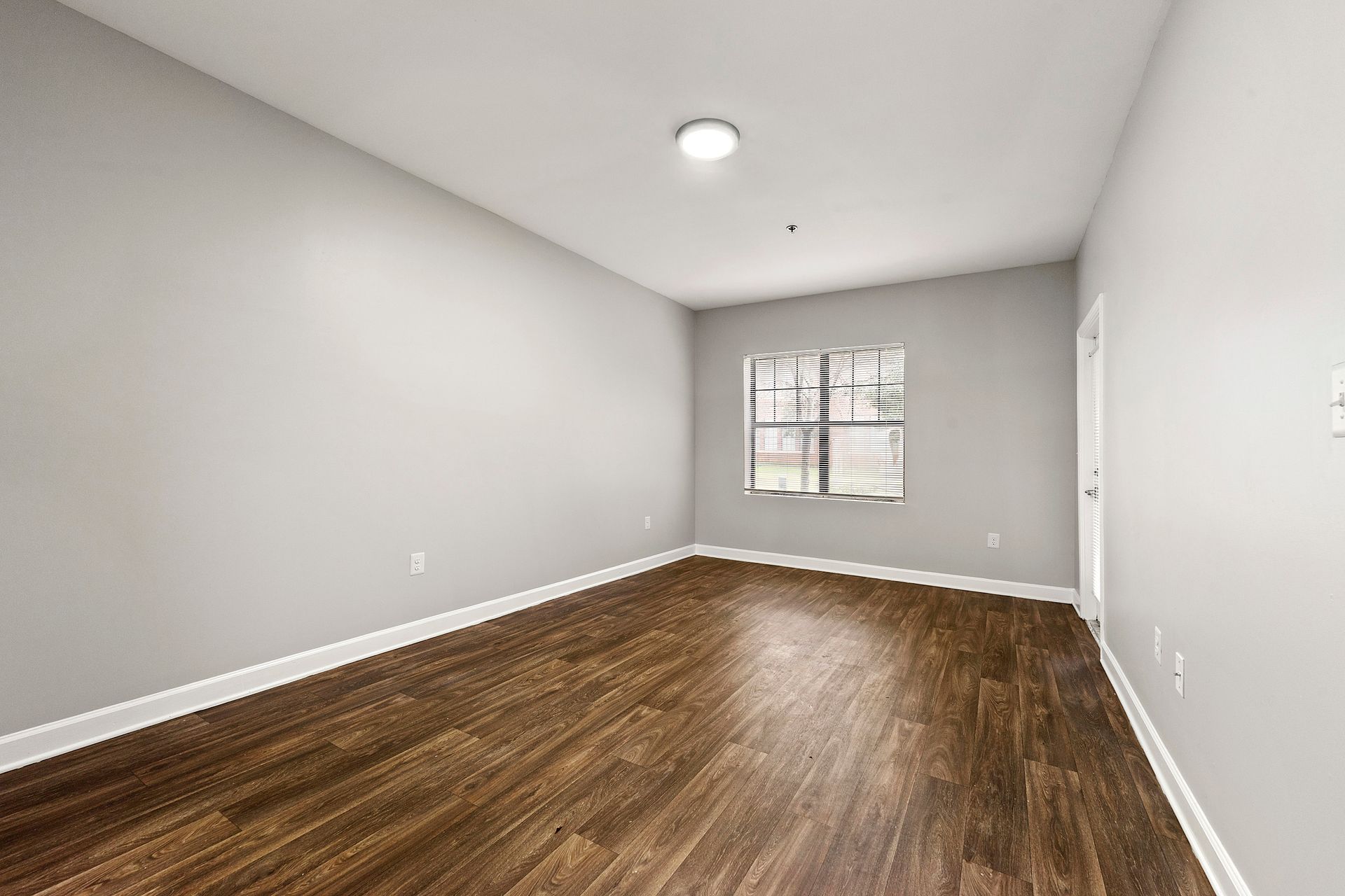 Empty gray room with hardwood floors and a window