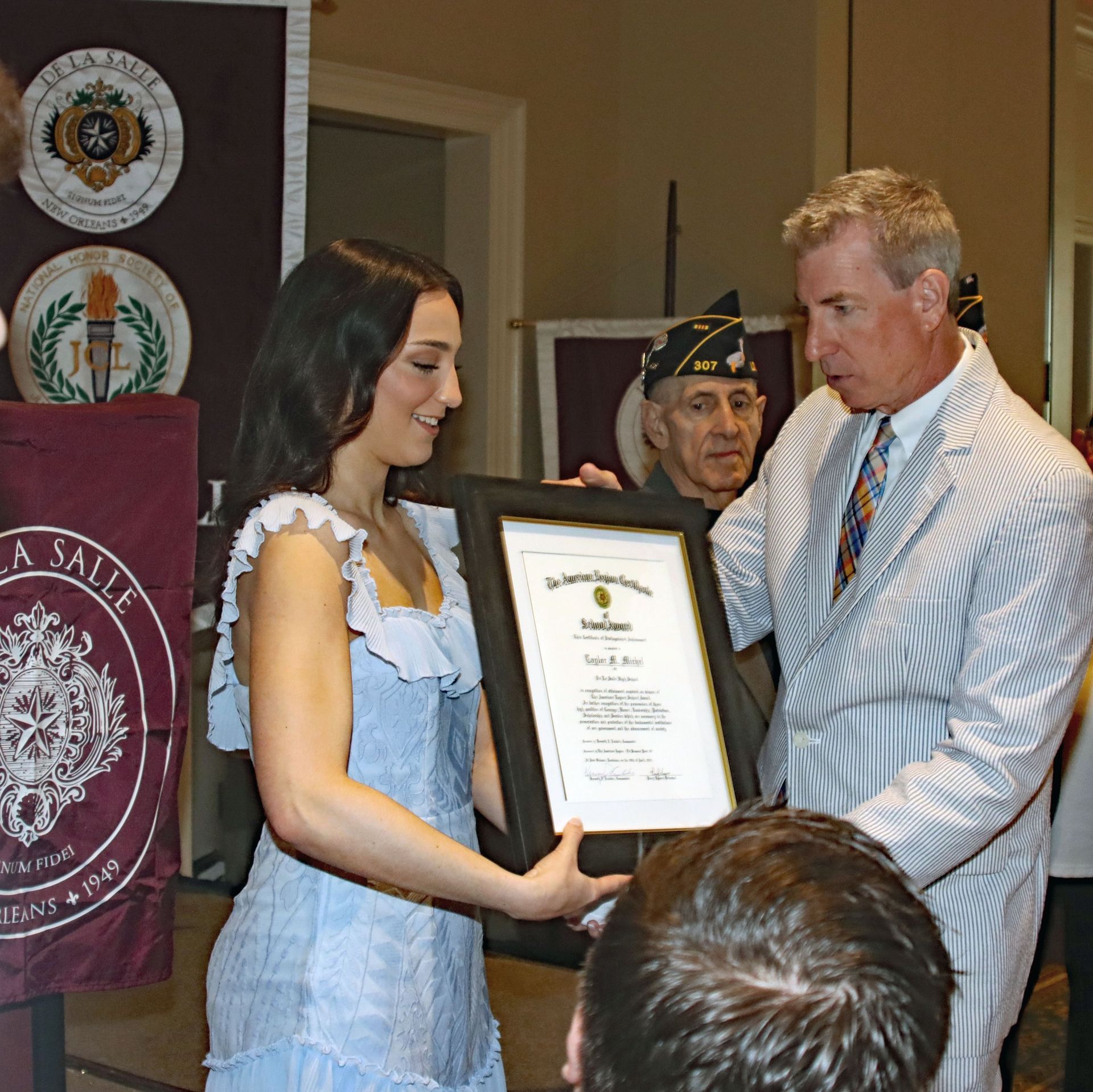 Woman and man present a framed certificate at a formal awards ceremony