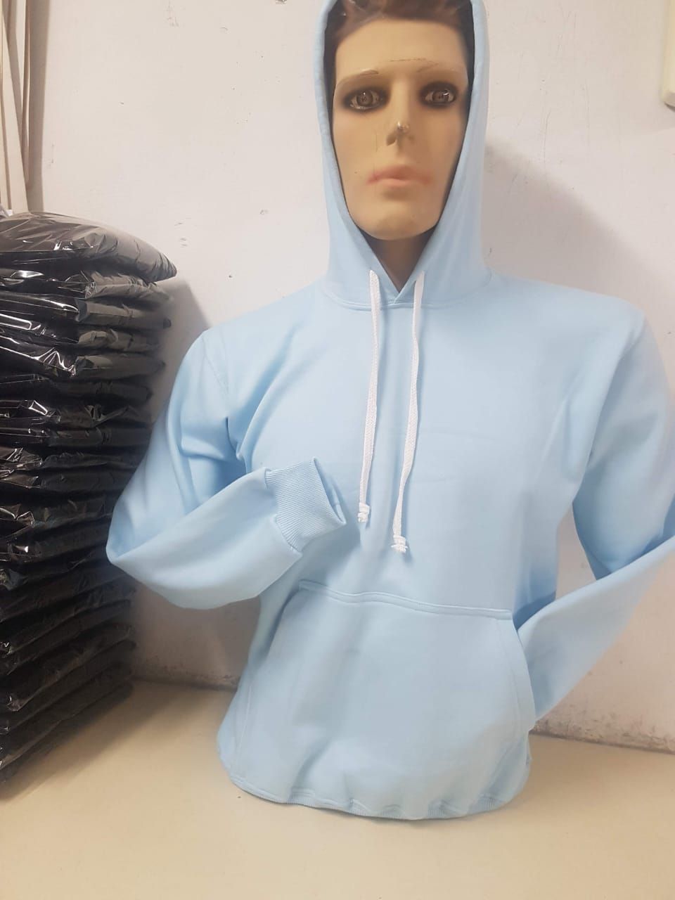 Una sudadera con capucha azul claro y cordón ajustable se exhibe en un maniquí