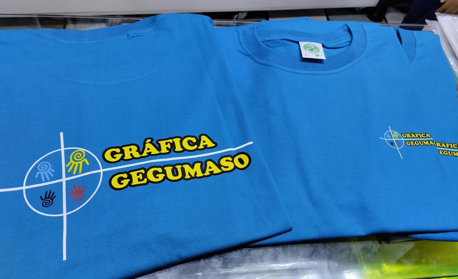 Dos camisetas azul claro muestran el logotipo