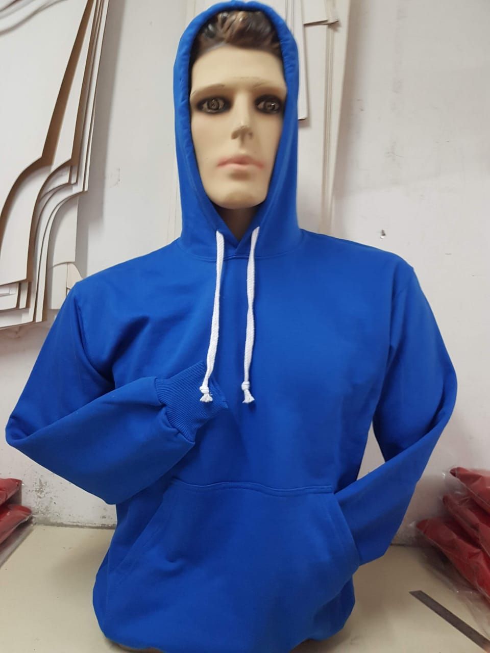 Una sudadera azul con capucha y cordones blancos se exhibe en un maniquí.