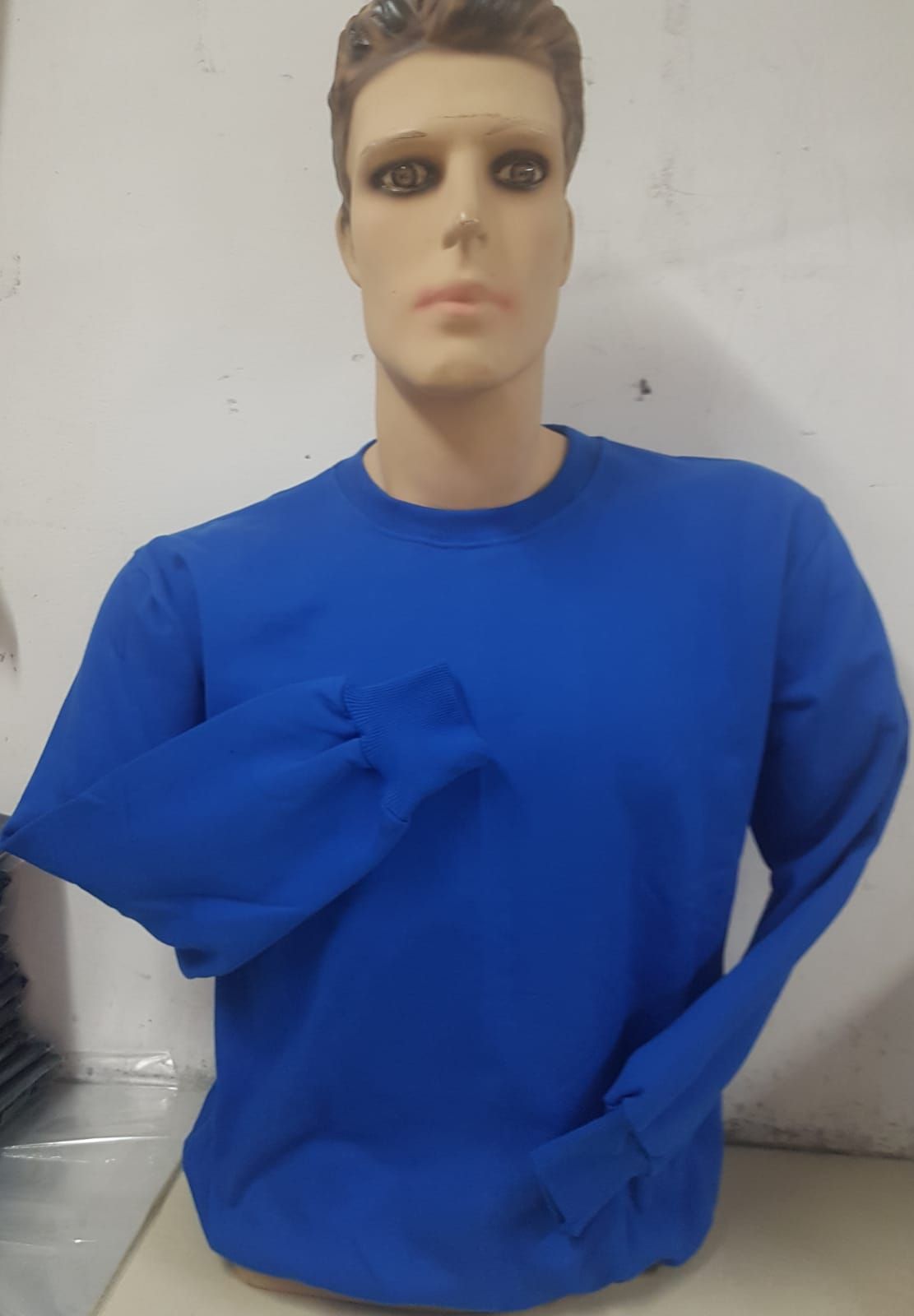 Un maniquí con una sudadera de cuello redondo de color azul marino liso sobre un fondo blanco roto.