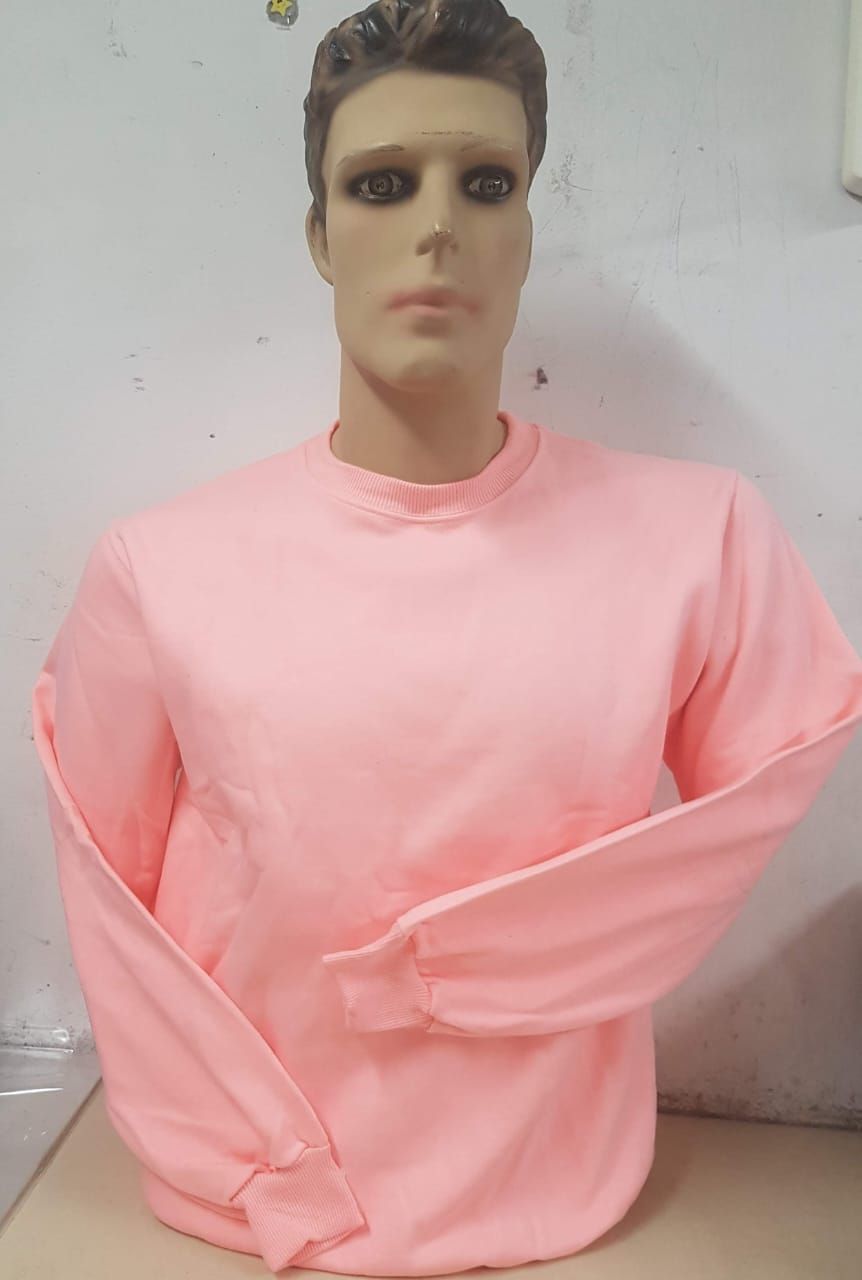 Un maniquí con un suéter liso de manga larga y cuello redondo de color rosa claro, colocado sobre una pared blanca lisa.