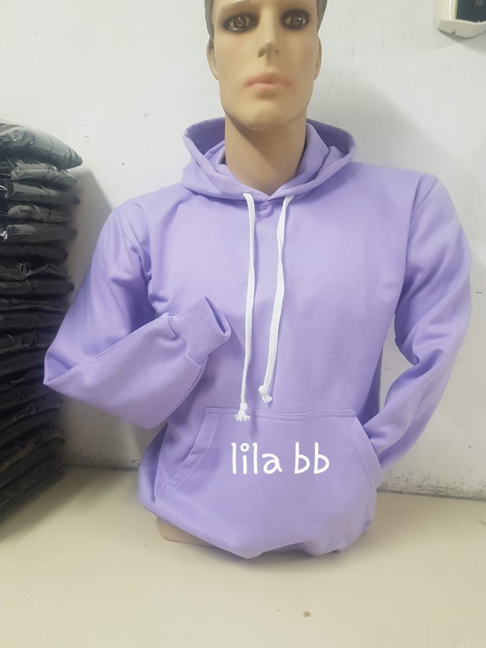Una sudadera con capucha lila, con cordón ajustable y bolsillo delantero, exhibida en el torso de un maniquí.