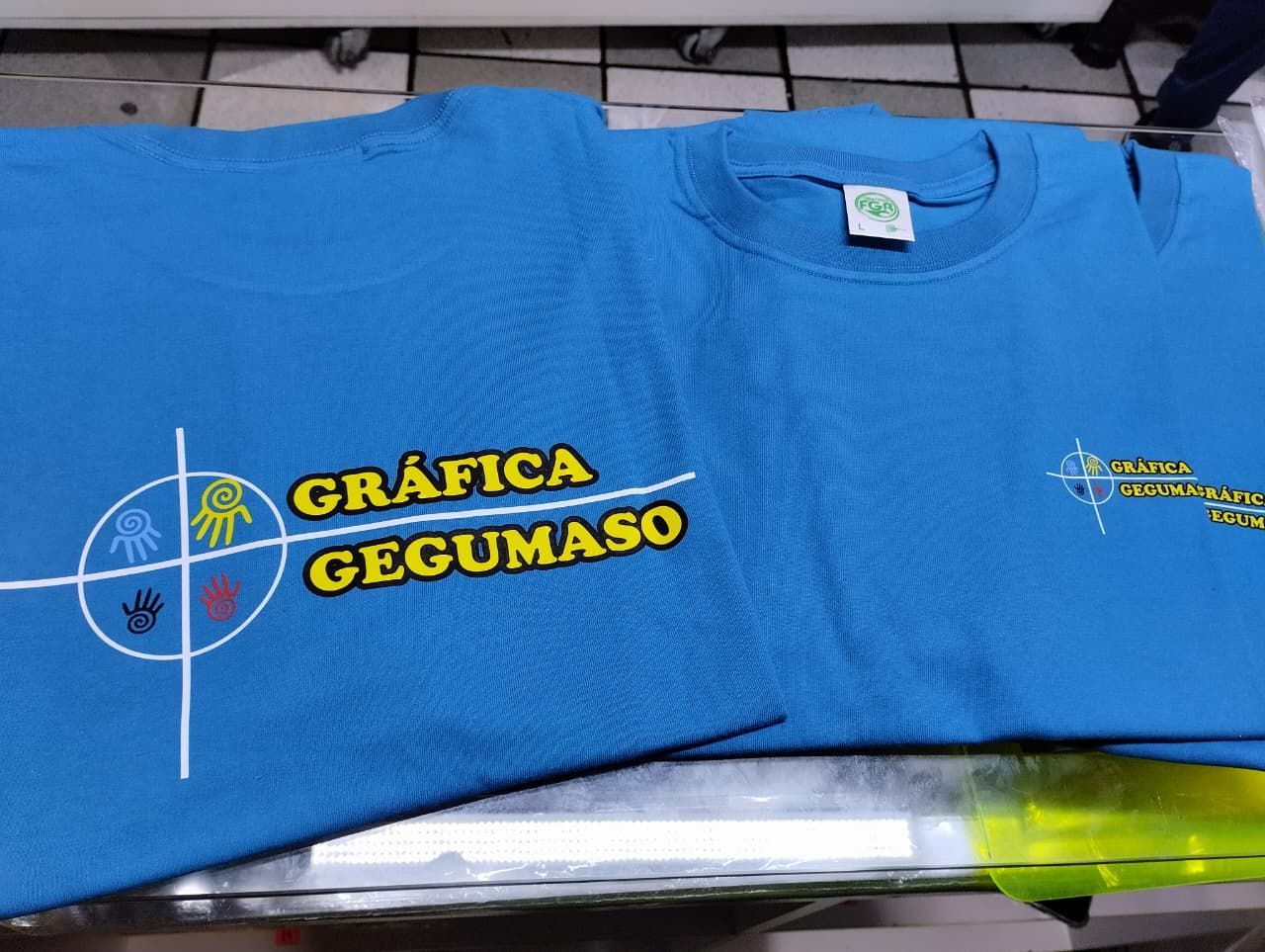 Dos camisetas de color azul brillante con el logotipo