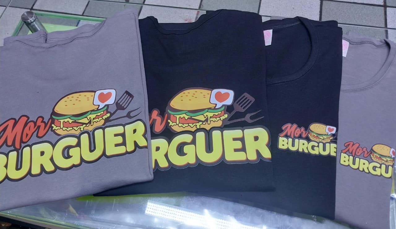Cuatro camisetas grises y negras dispuestas sobre una superficie