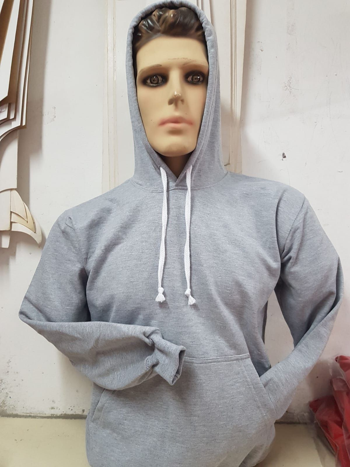 Sudadera con capucha de color gris claro y cordón ajustable, mostrada en un maniquí sobre un fondo blanco.