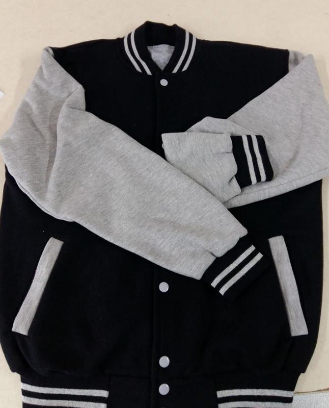 Una chaqueta universitaria negra con mangas, cuello y puños acanalados de color gris jaspeado con detalles de rayas blancas.