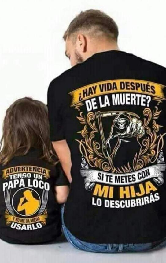 Una persona y un niño vistos de espaldas, con camisetas negras iguales con diseños gráficos y texto en español.