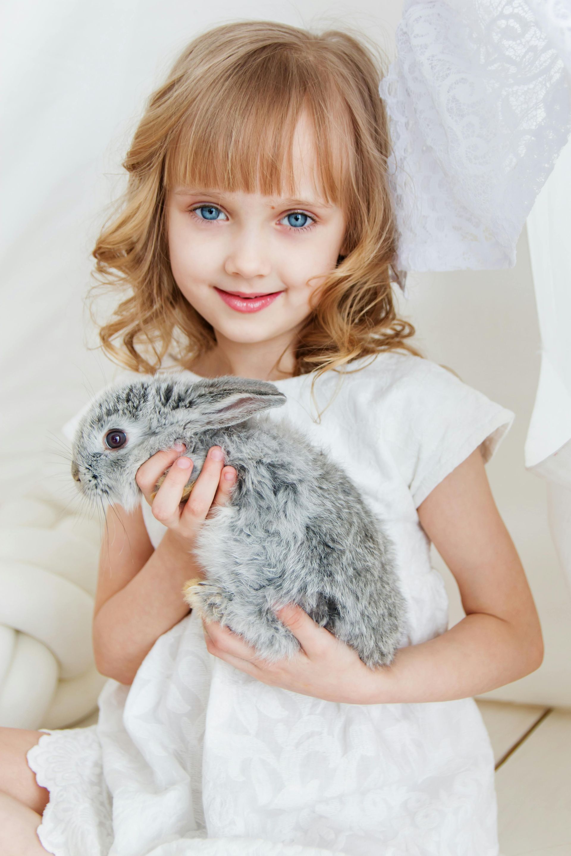 Una niña rubia de ojos azules, vestida con un vestido blanco