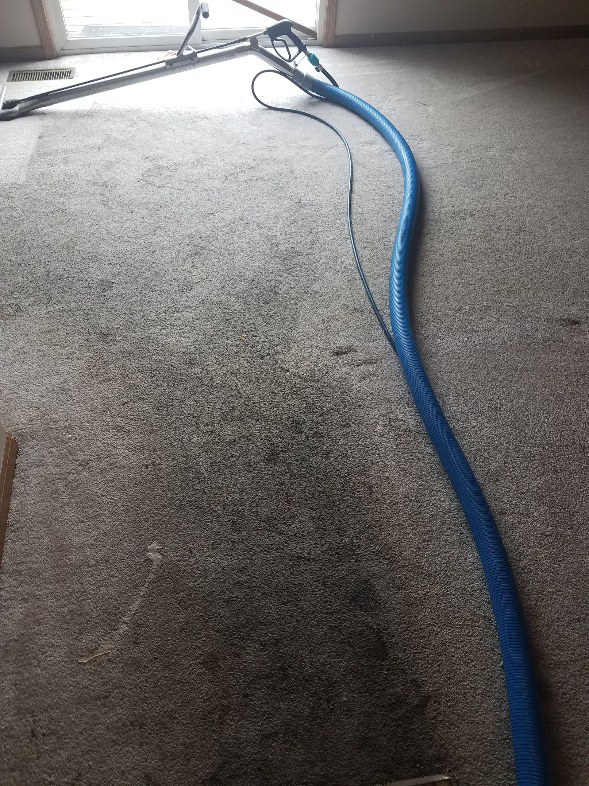 A vacuum cleaner is sitting on top of a dirty carpet.