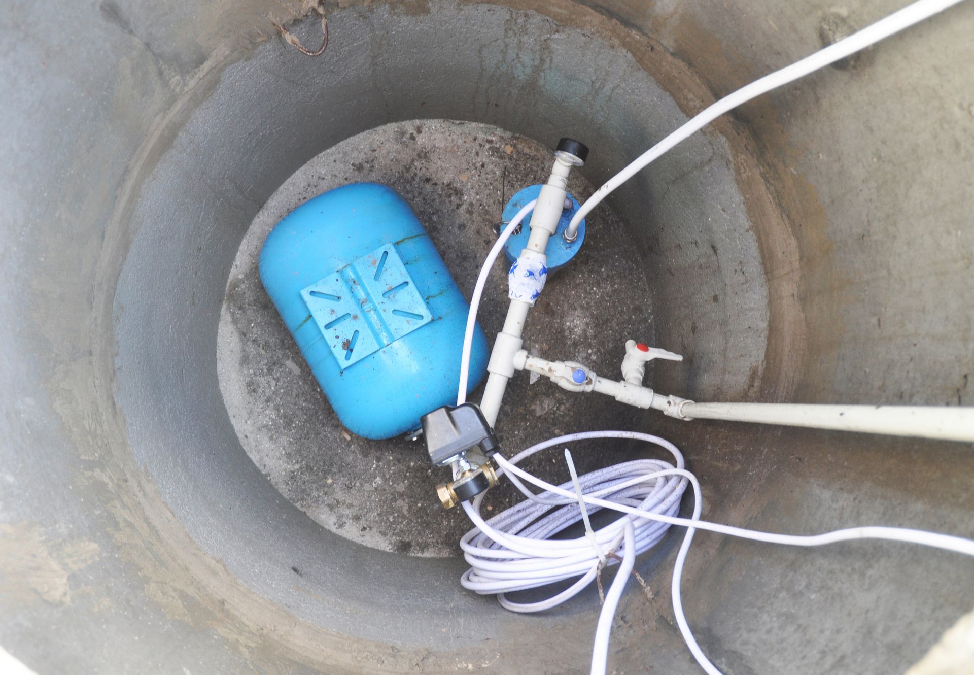 A blue tank is sitting in the middle of a concrete well.