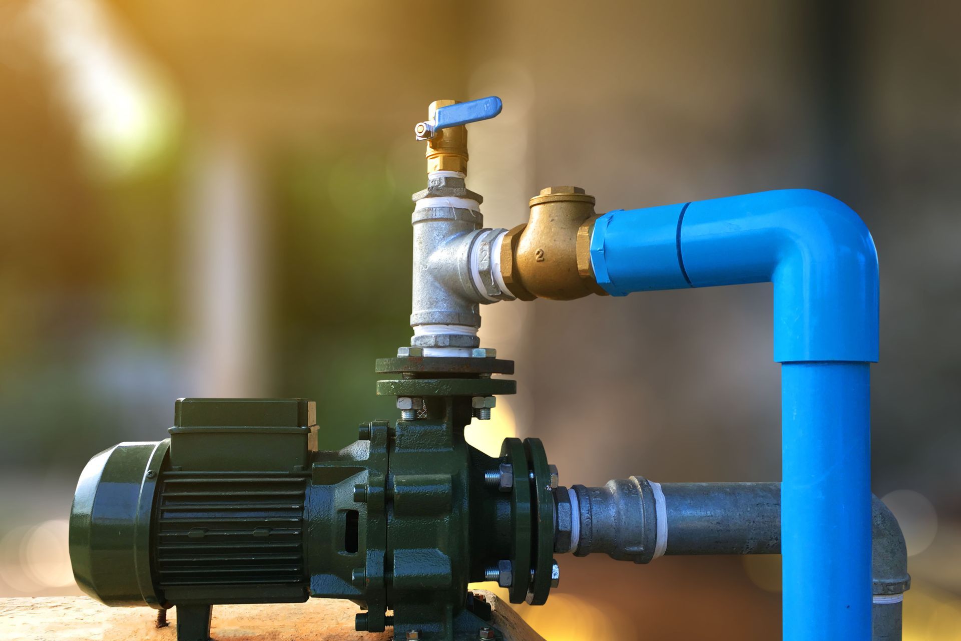 A big water pump motor is connected to blue pipes and a valve. A big water pump motor is connected to blue pipes and a valve.