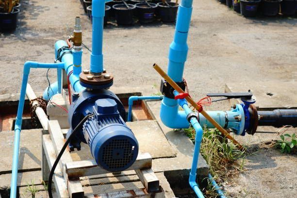 A blue water pump is sitting next to a bunch of blue pipes.