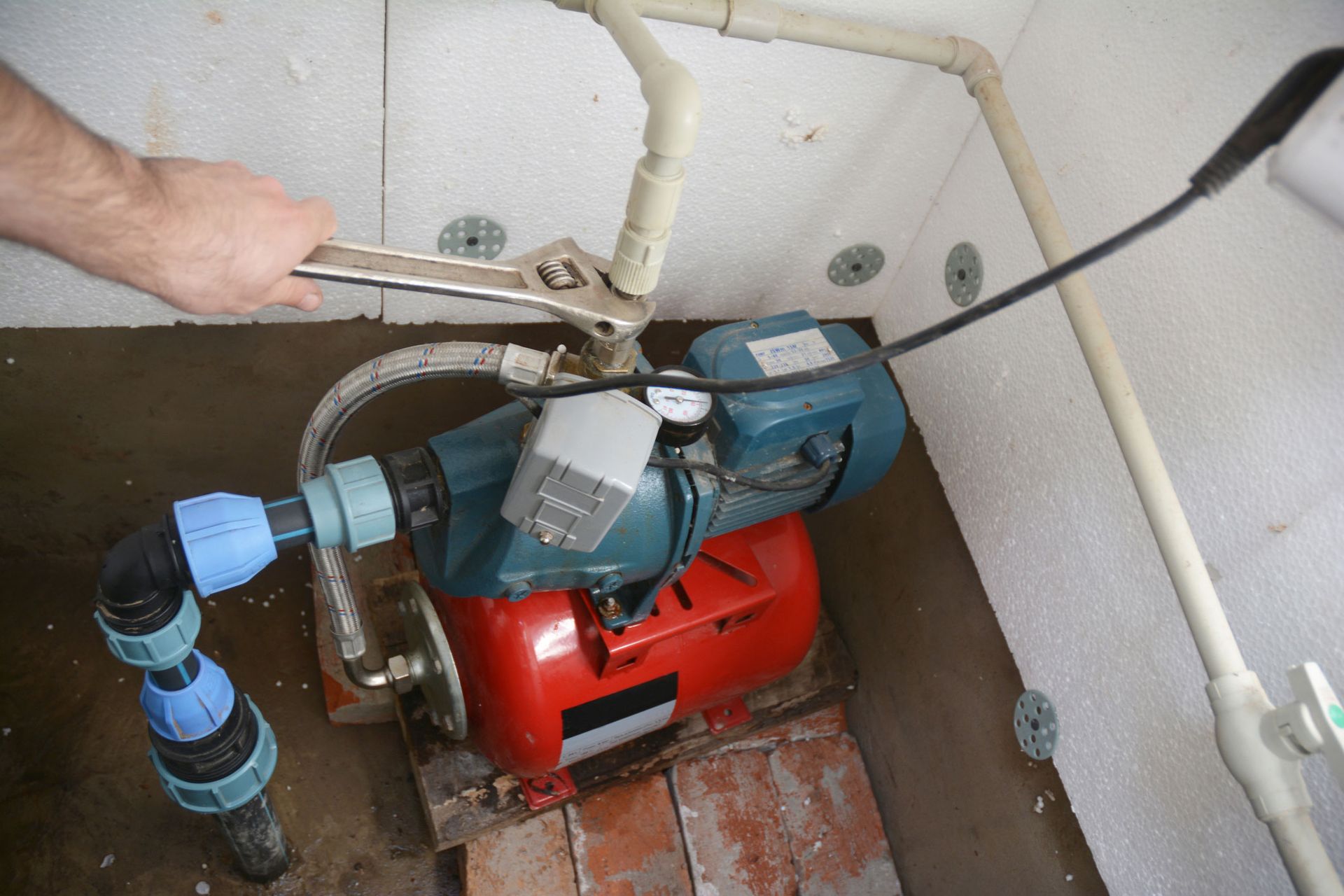 Contractor installing and repairing a water pumping station with a wrench.