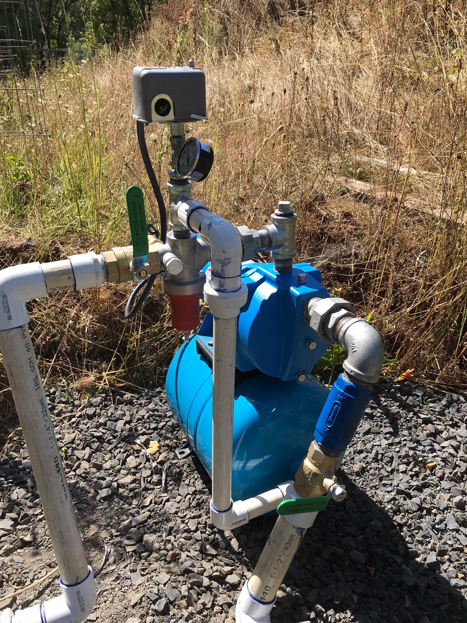 A water pump is sitting on the ground next to some pipes.