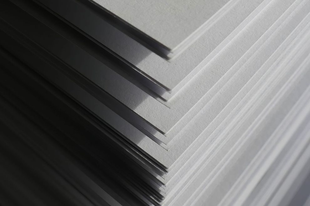 Primo piano astratto di lamiere metalliche sovrapposte con bordi diagonali netti, nei toni del nero e dell'argento.