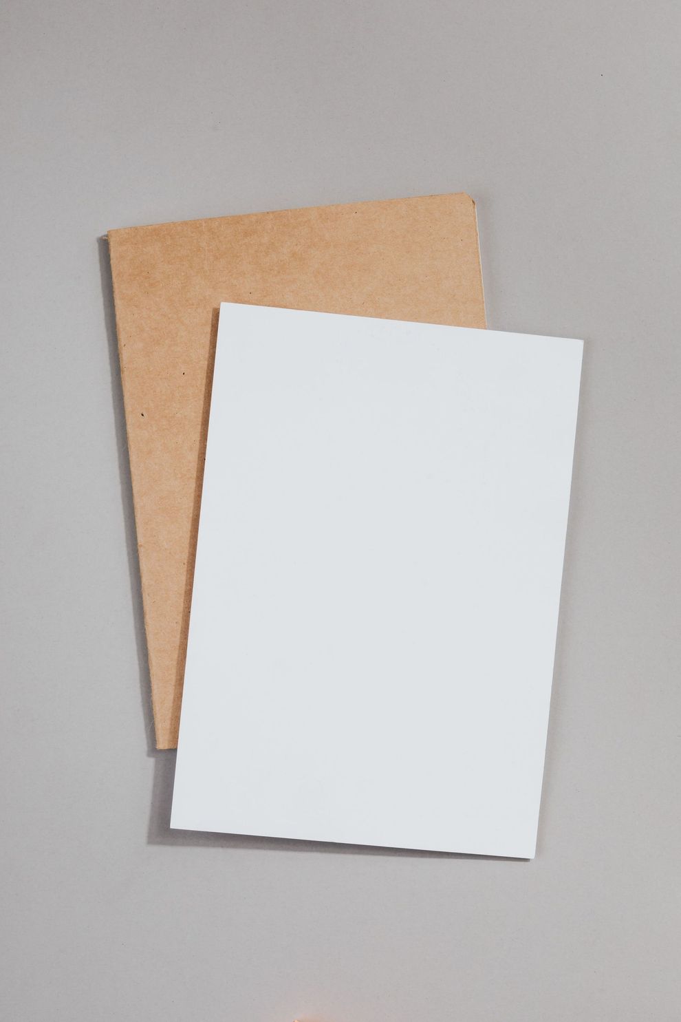 Due cartoncini bianchi sovrapposti, uno bianco e uno beige, su sfondo grigio.
