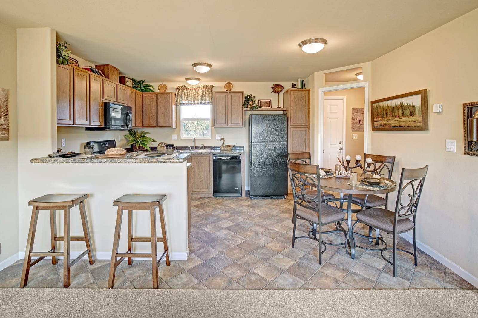 Kitchen with wooden cabinets, breakfast bar, and round dining table with four chairs.