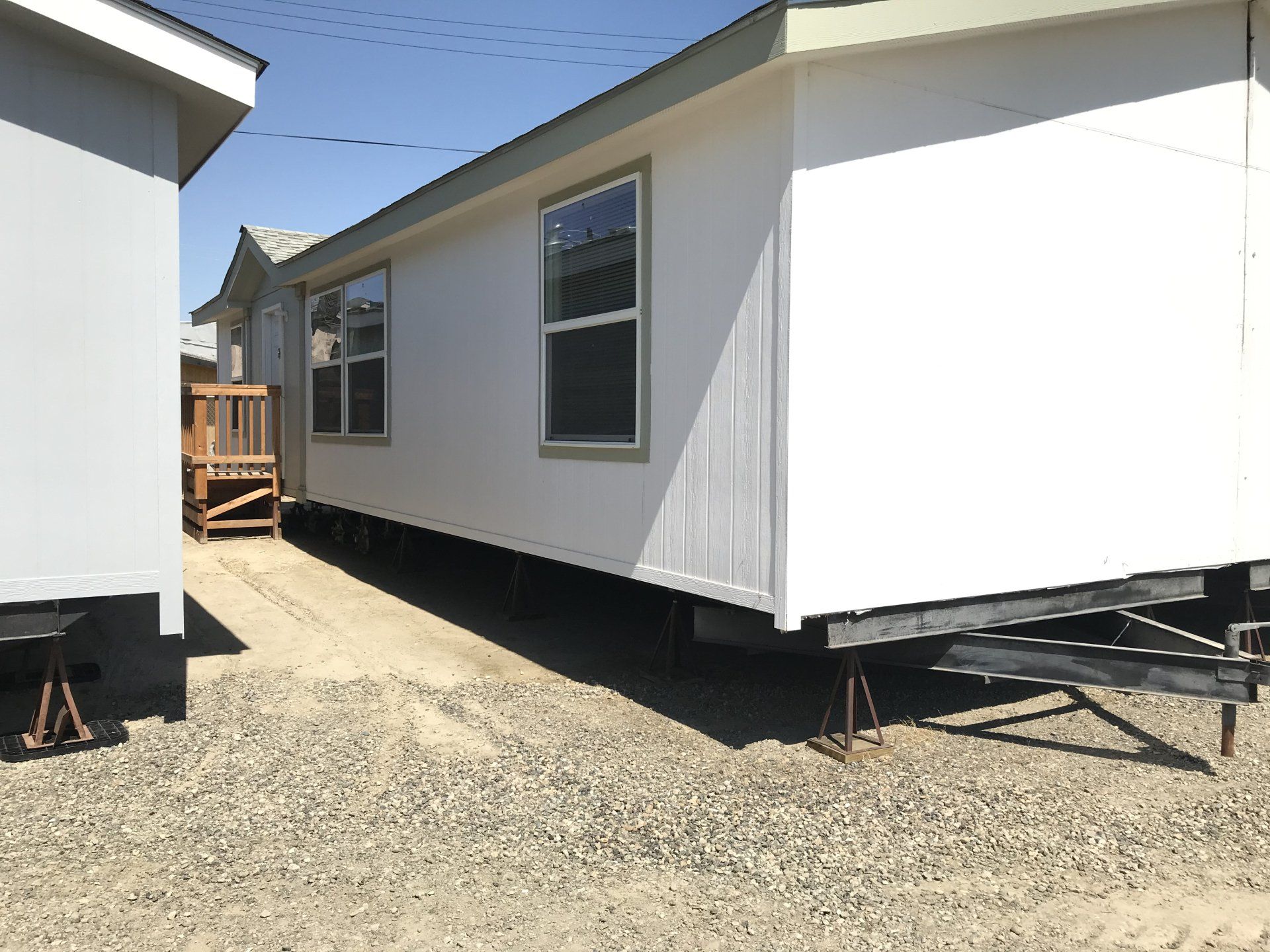 White modular home on gravel with a light blue building to the left.