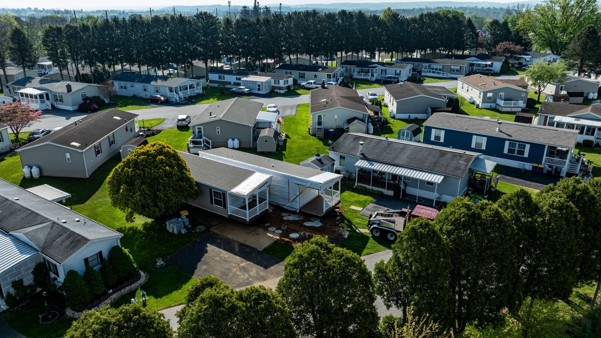 Aerial view of a mobile home community with landscaped yards and tree-lined streets.