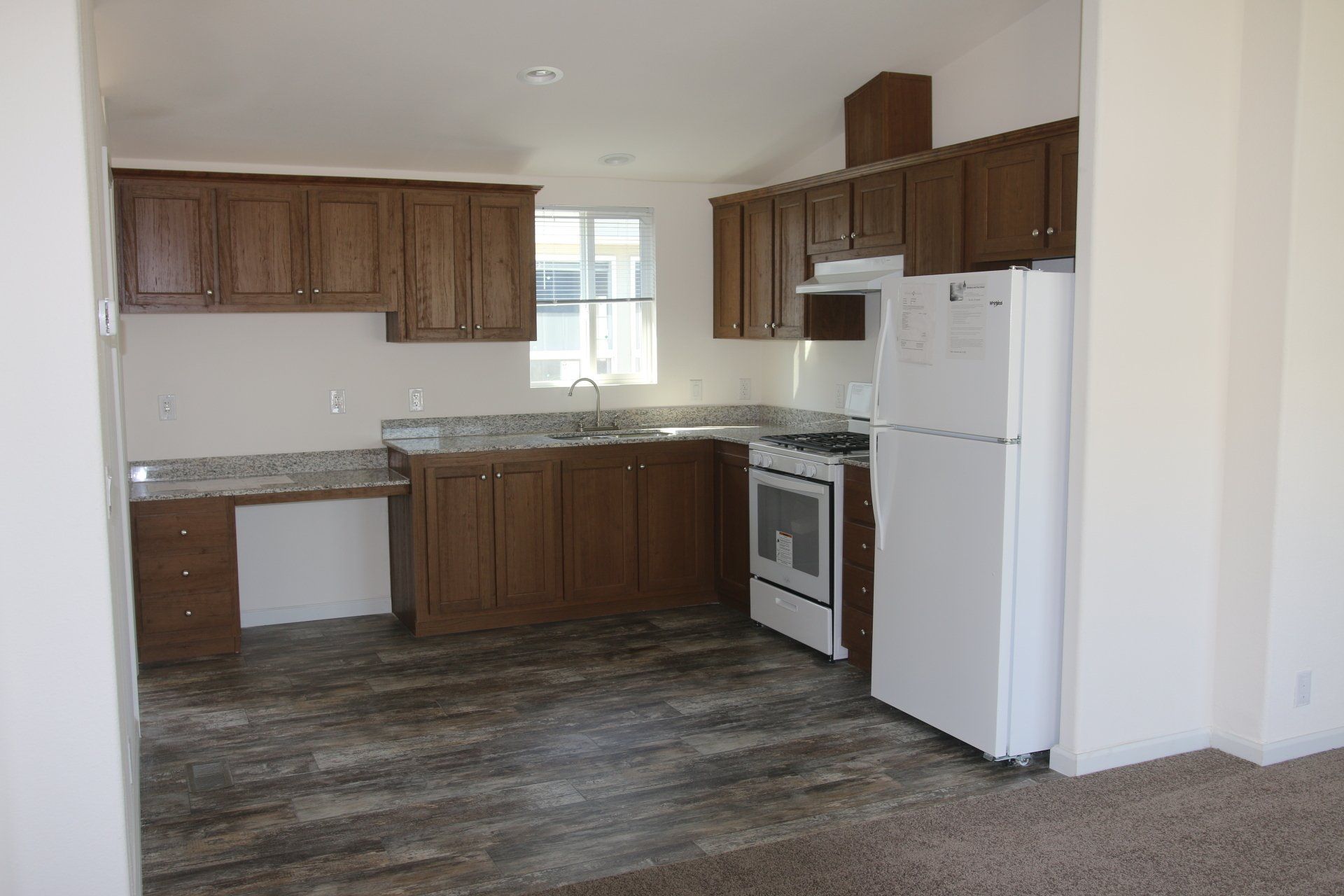Kitchen with brown cabinets, white appliances, and gray countertops.
