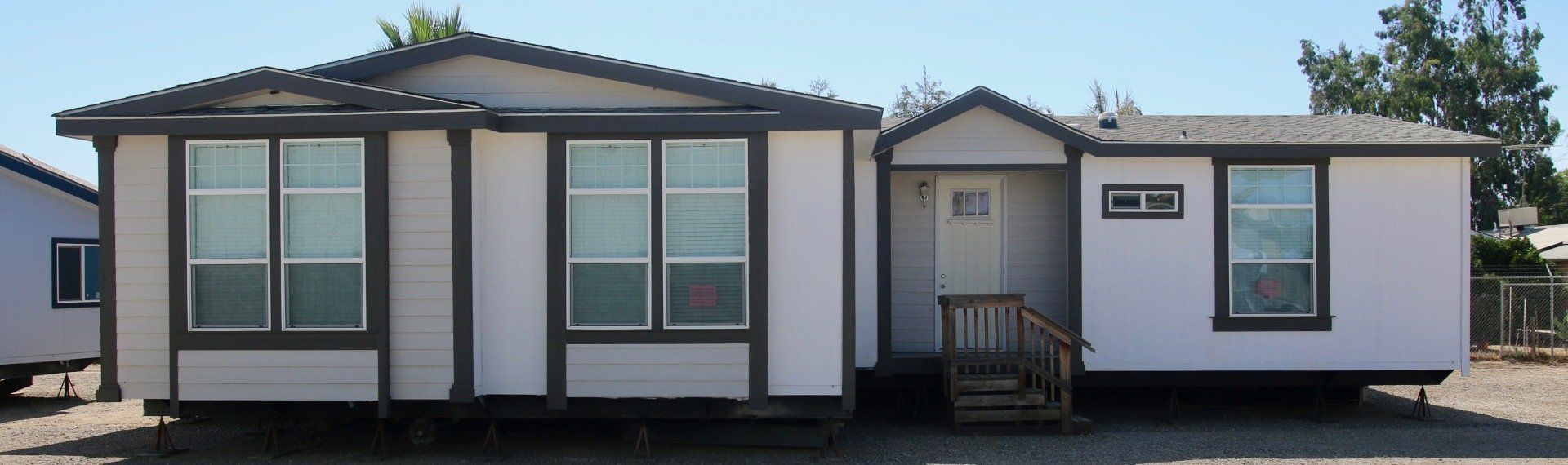 Modular home with light gray siding, dark trim, and a small front porch.