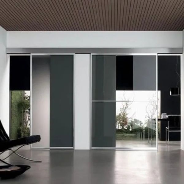 Interno moderno e minimalista con porte scorrevoli in vetro, pareti grigie e poltrona nera.