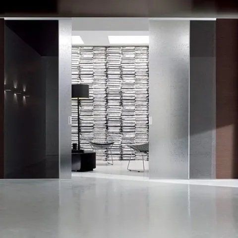 Atrio di un moderno ufficio con porte in vetro satinato e una parete di pile di carte alle loro spalle.