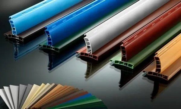 Vari campioni di tubi e profili in PVC colorati, disposti diagonalmente su una superficie riflettente.