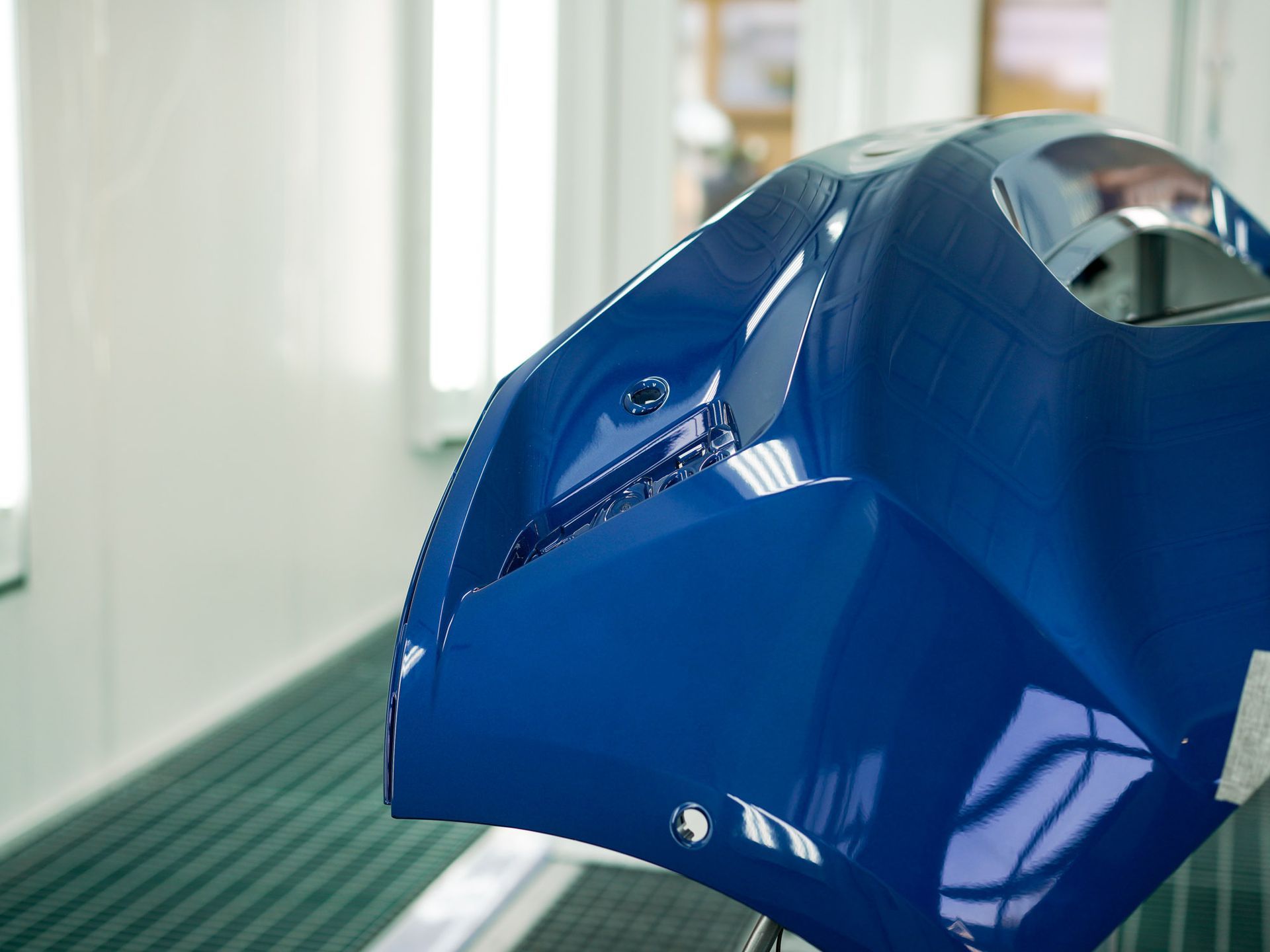 Eine blaue Autostoßstange steht in einer Lackierkammer