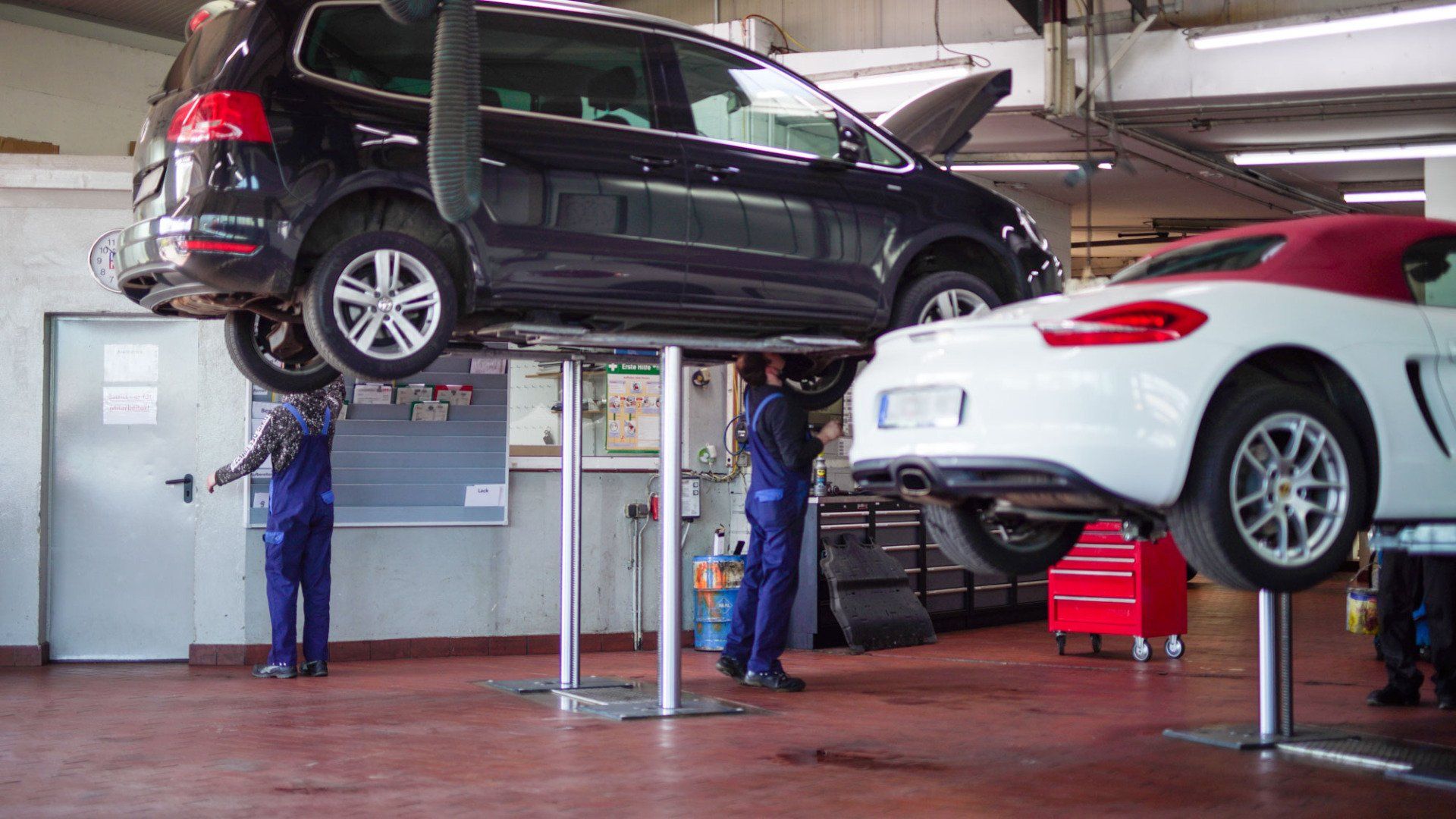 Zwei Autos stehen auf einer Hebebühne in der Werkstatt.