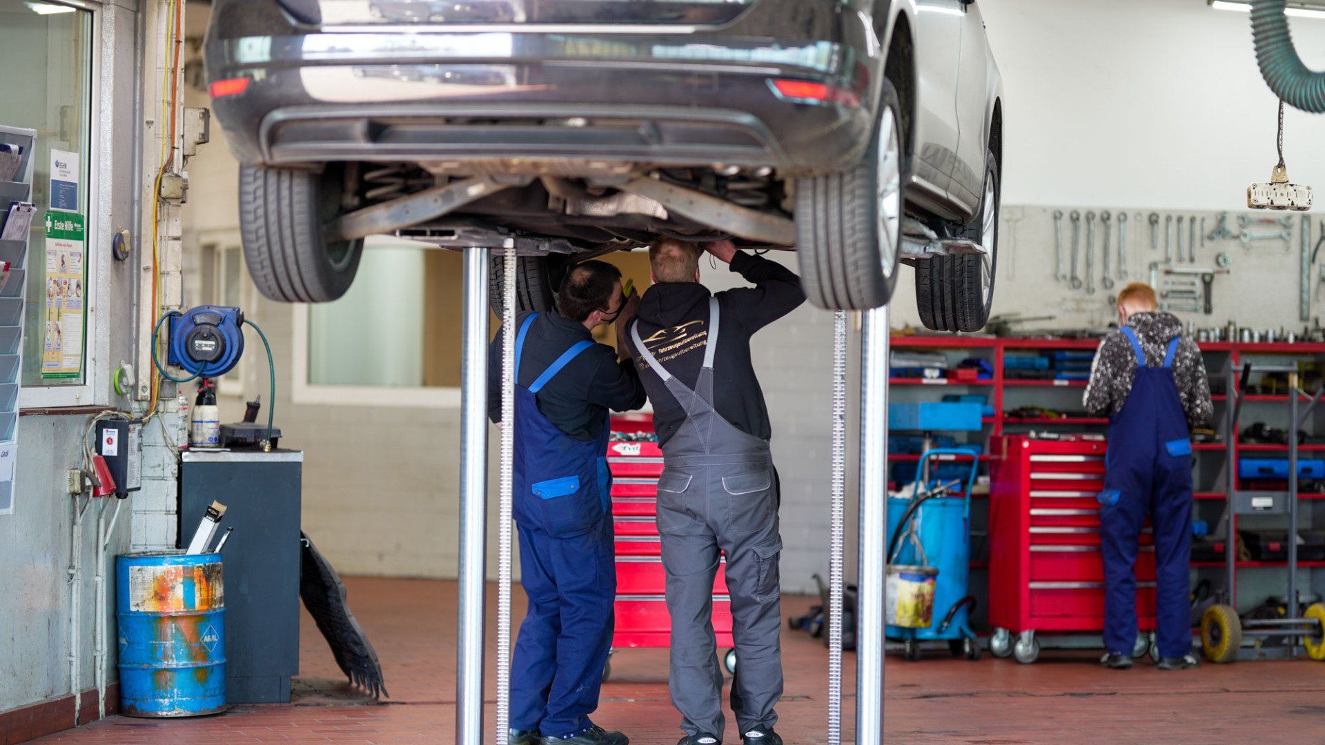 Eine Gruppe von Mechanikern arbeitet in einer Werkstatt an einem Auto.