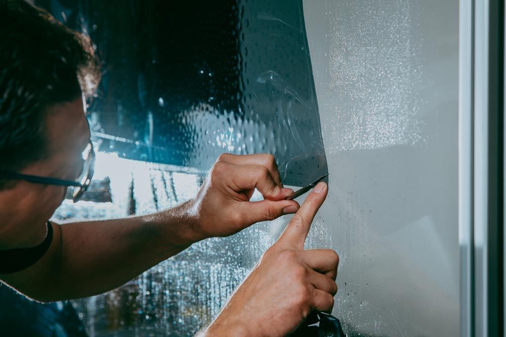 Gloved hand applying a coating to a shiny red car surface.