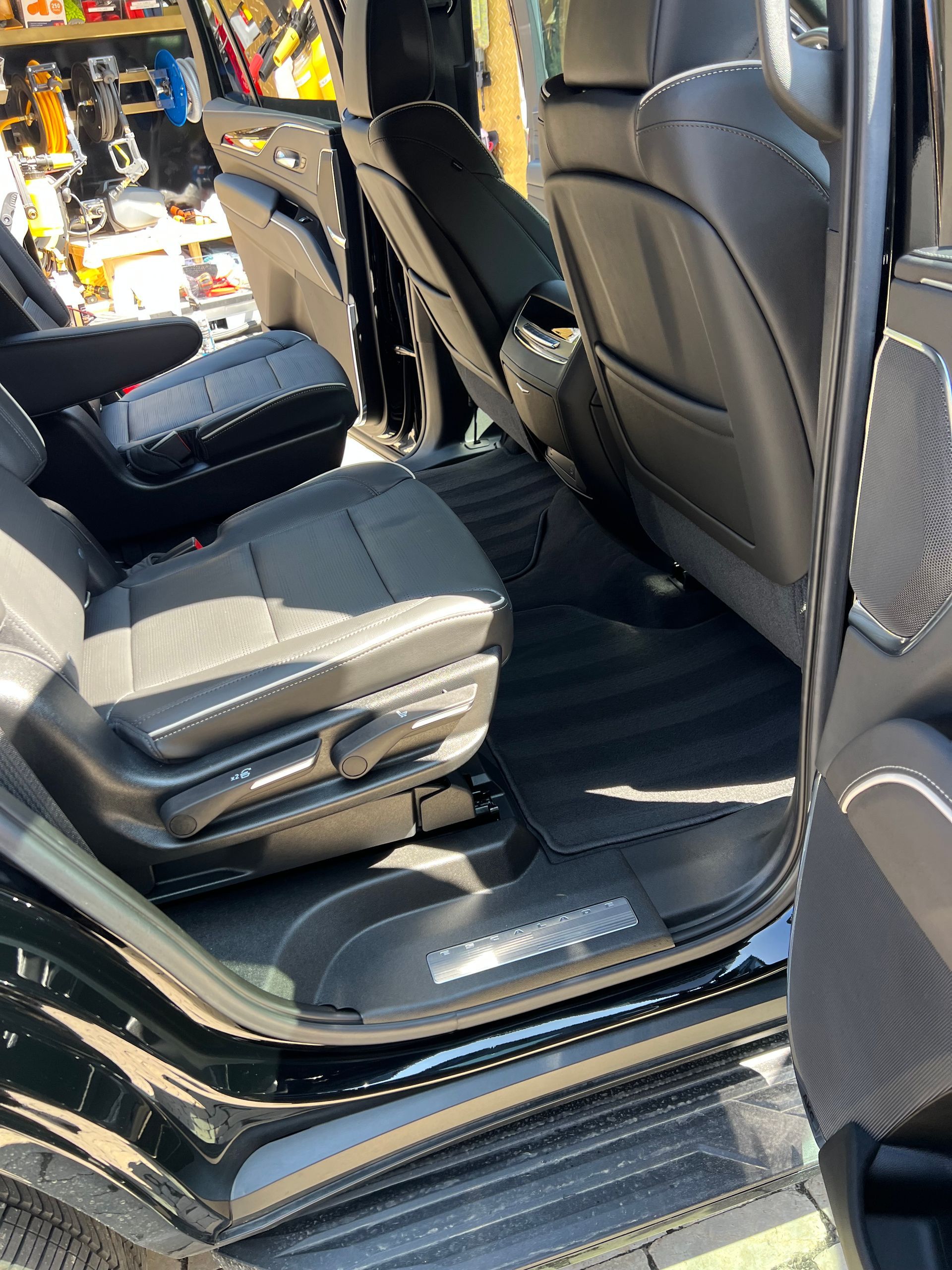 Interior view of a black car's back seat with leather seats and a clean floor mat.