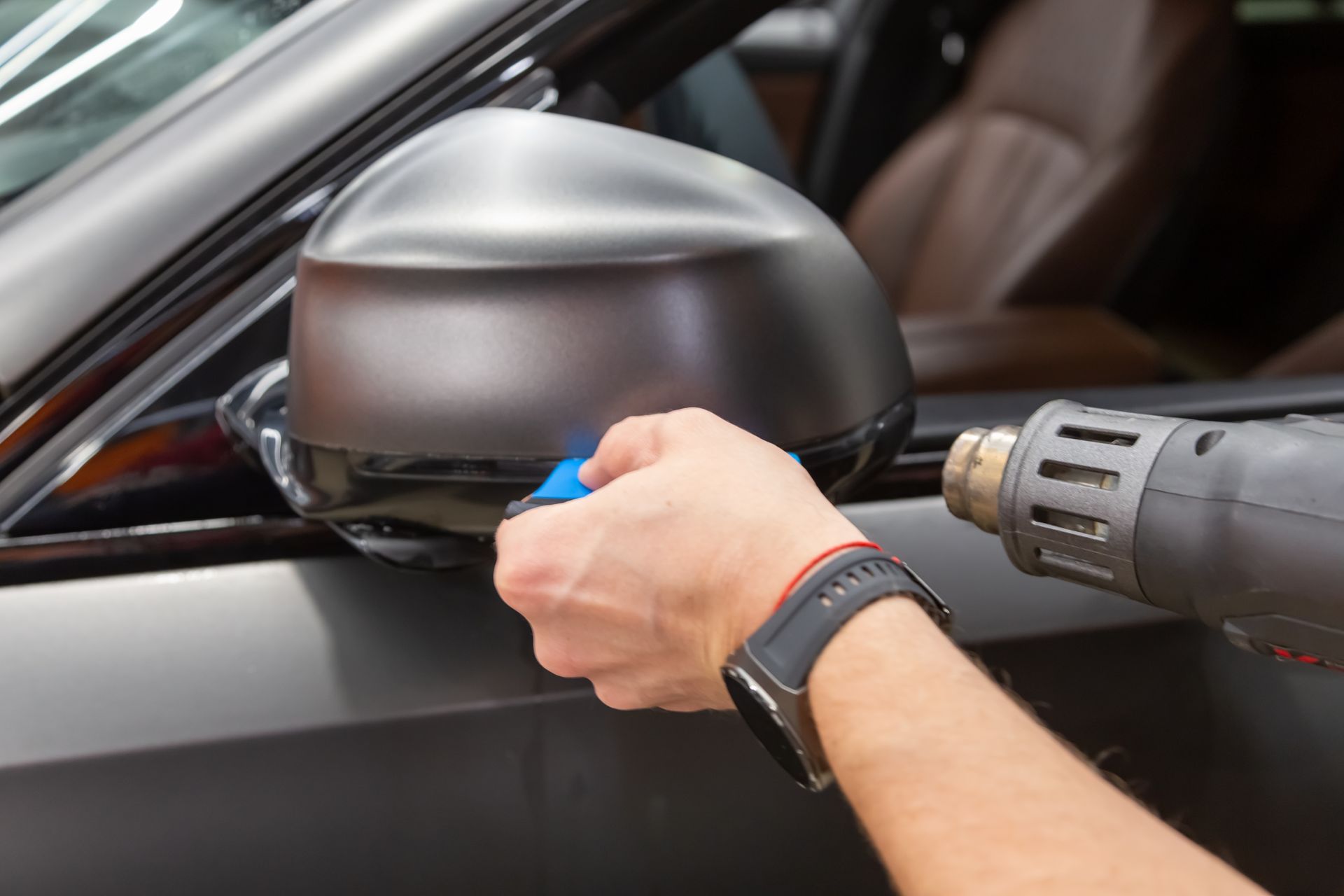 Gloved hand applying a coating to a shiny red car surface.