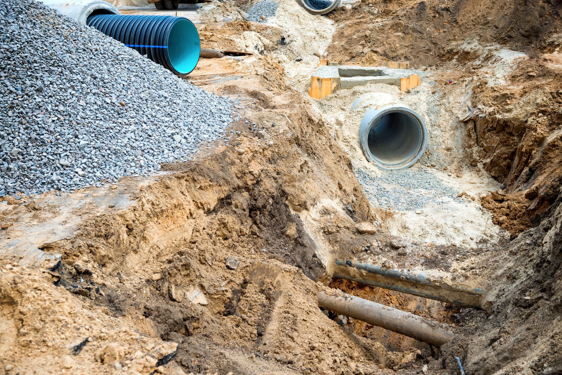 Concrete drainage pipe surrounded by gray rocks in a grassy roadside area