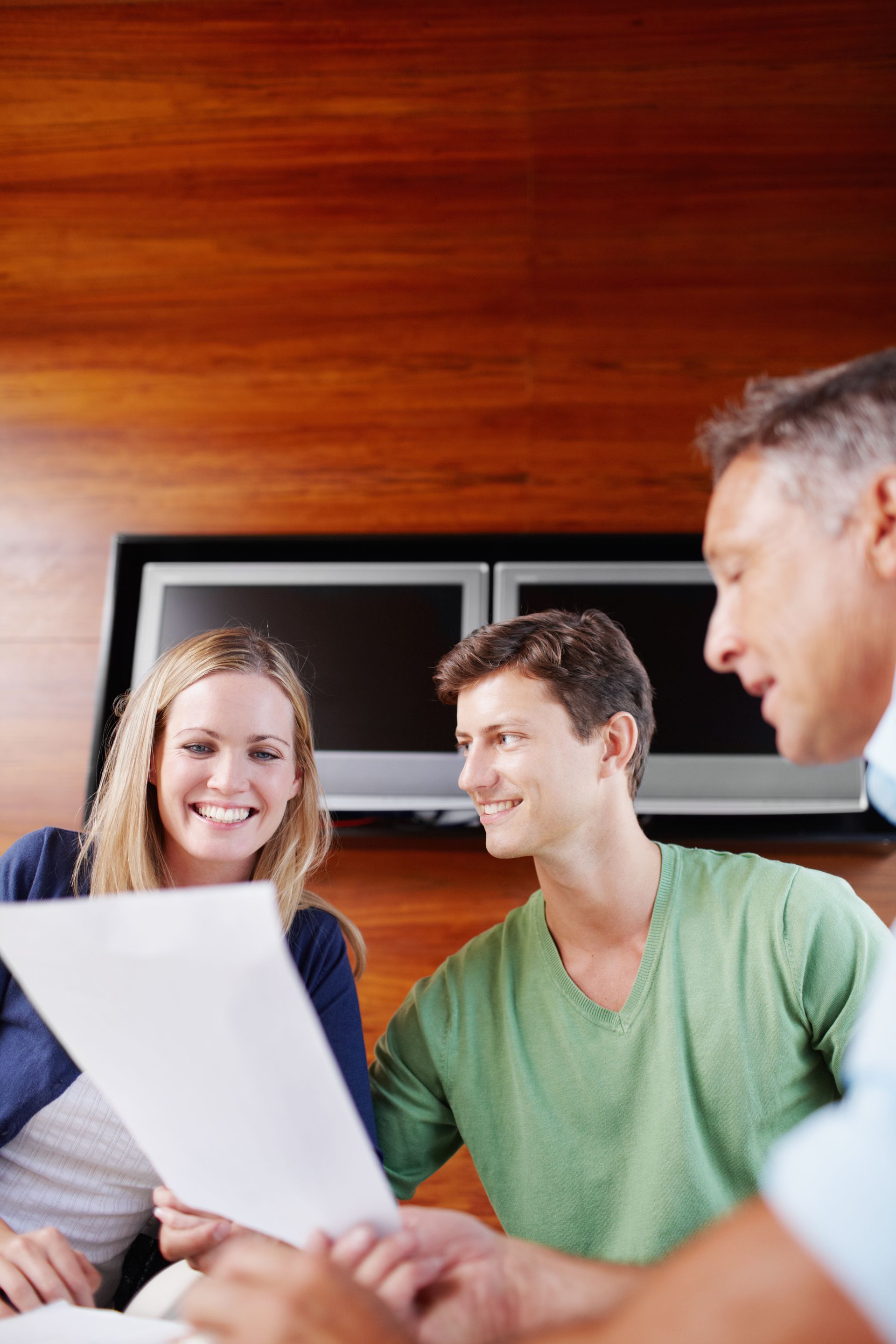 Three coworkers smiling over a document in a modern office conference room