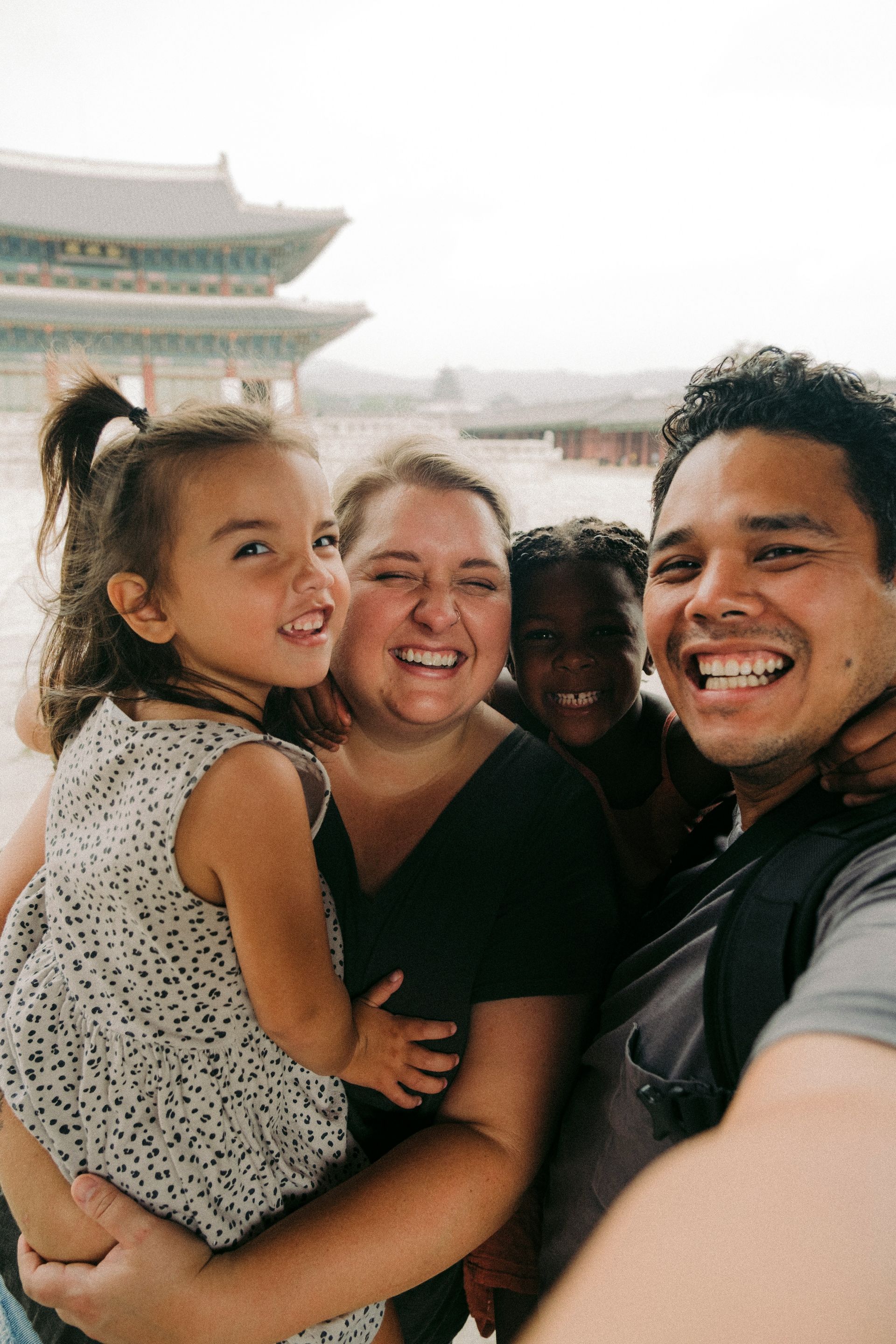 Smiling family taking a selfie in front of a traditional building outdoors