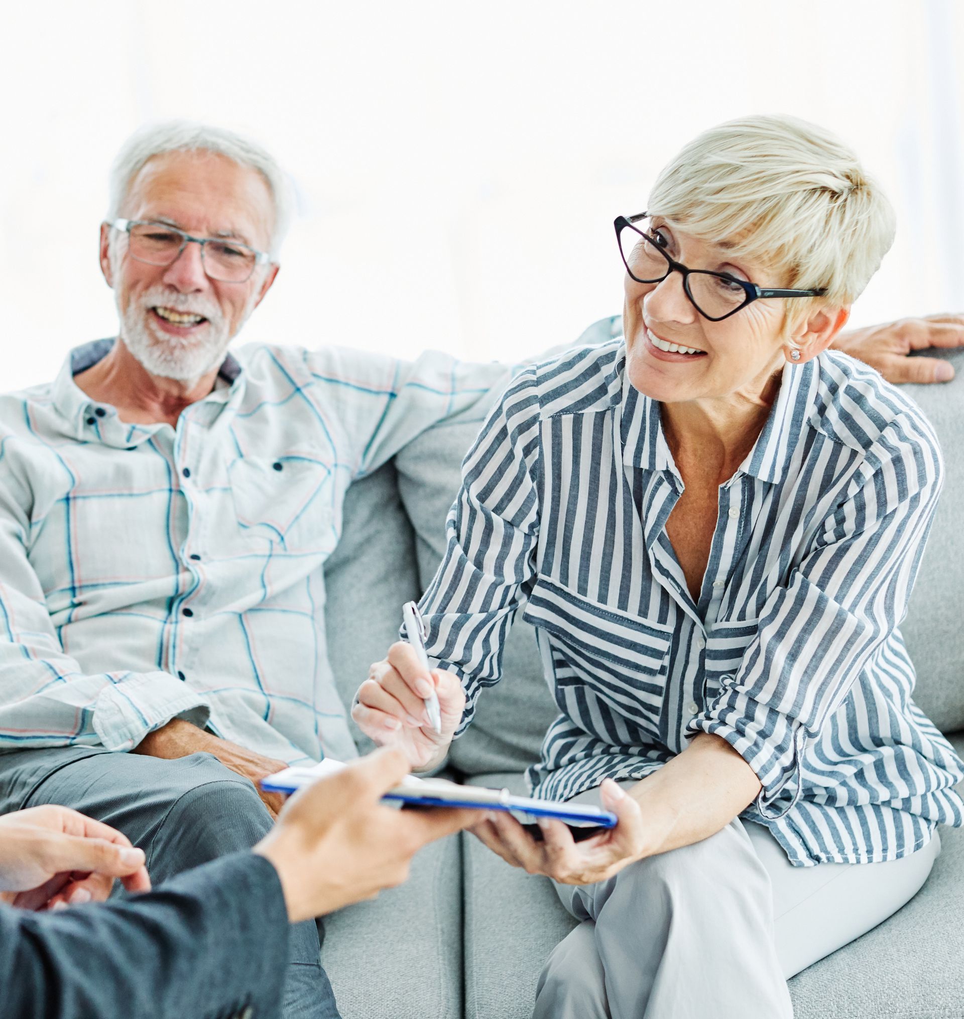 Two smiling people on a couch looking at a smartphone together