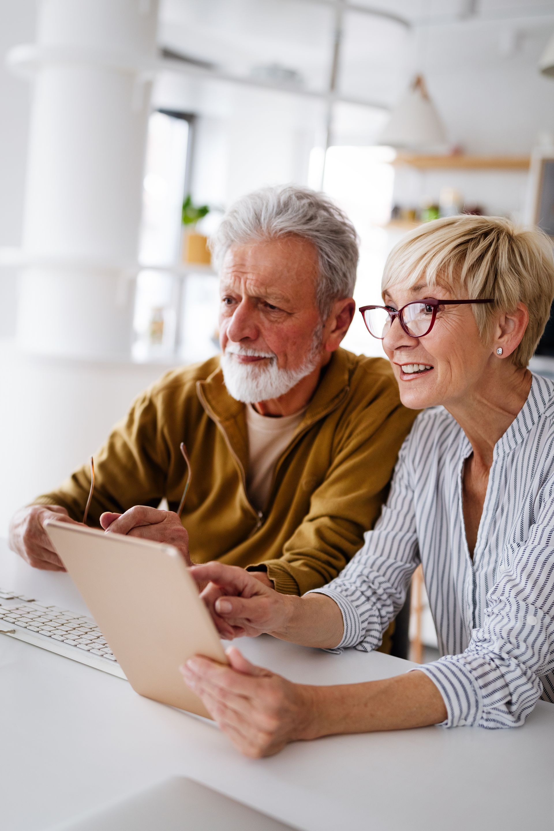 Two people smiling at a laptop in a bright room