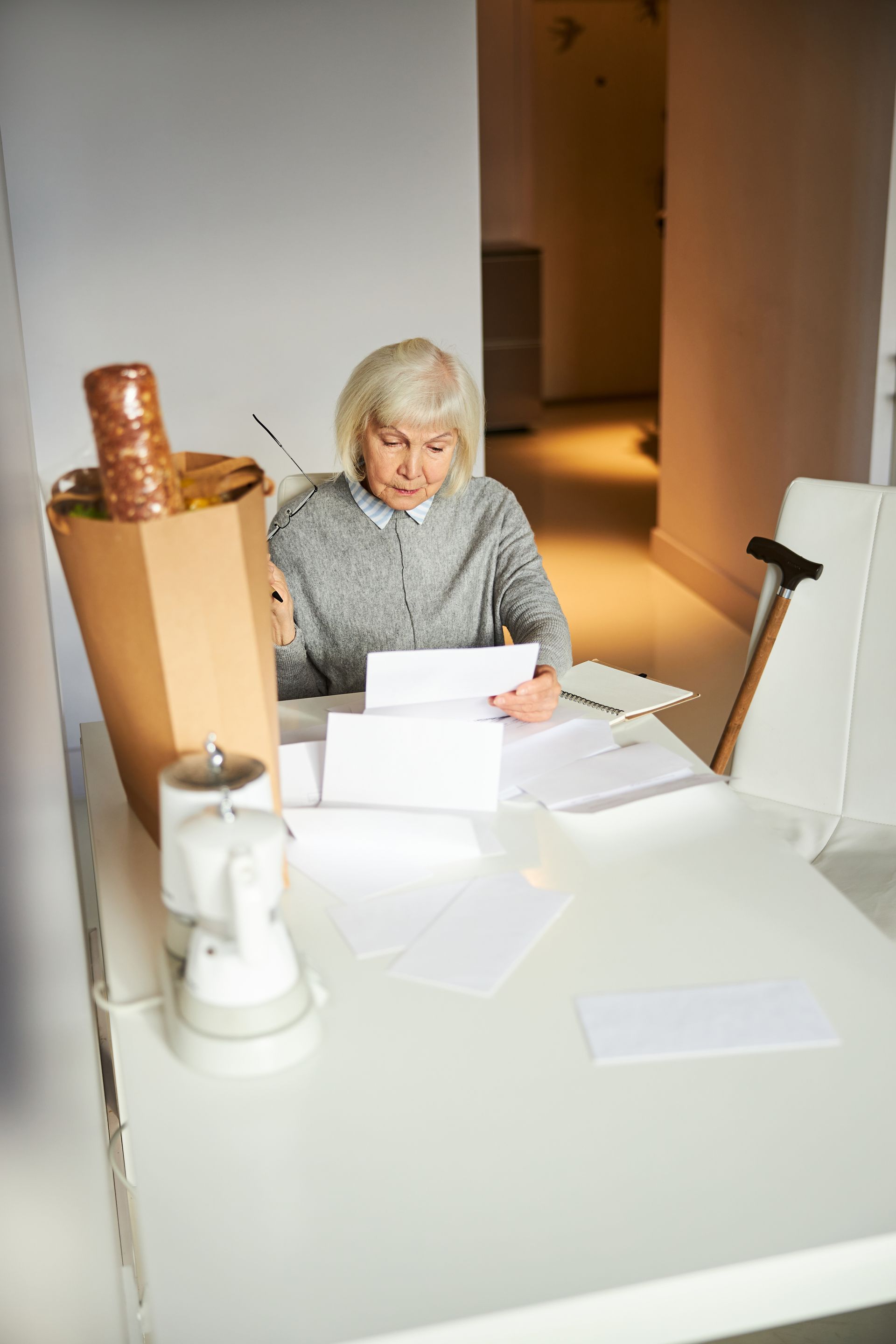 Person reading papers at a white table in a modern office or studio, with lamps and boxes nearby