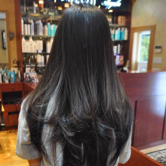 A woman with long black hair is standing in a salon